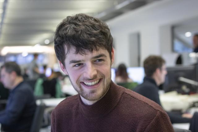 headshot of liam briggs, looking off to side, smiling laughing