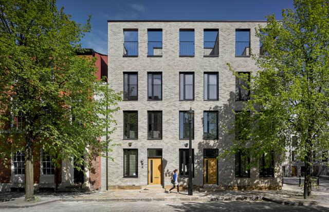 a lady walks past grey brick tonwhouses