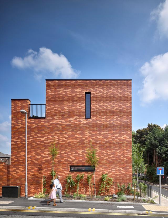 Man and girl walking past the side of a building.