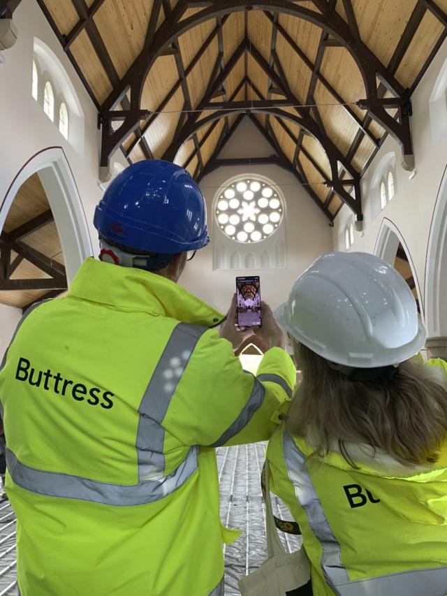 two buttress team members in hi vis on church site back to camera, taking picture