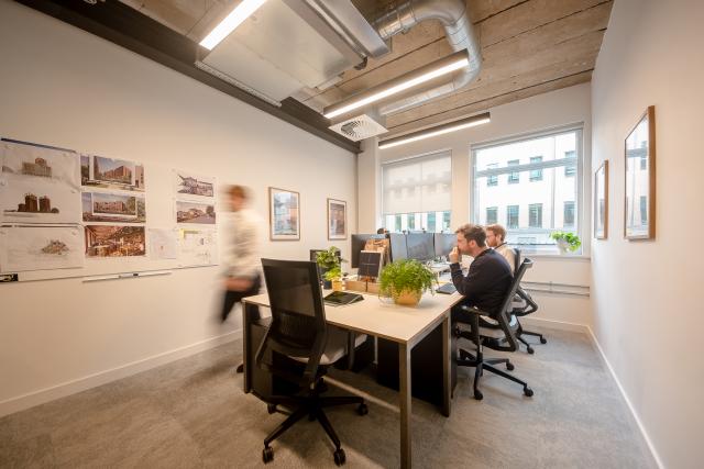 An office space with exposed services on the ceiling