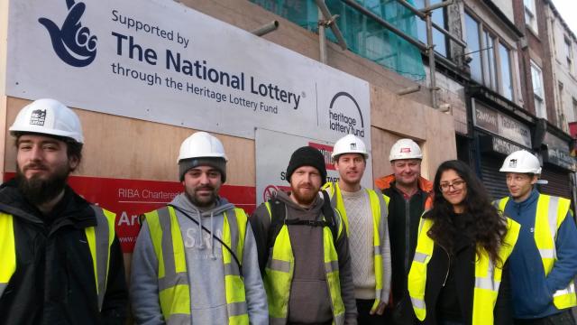 group of people in hi-vis and hard hats posing infront of eritage lottery funded building site