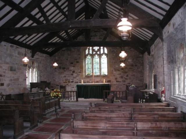 interior of church, dimly lit with rows of dark wood pews