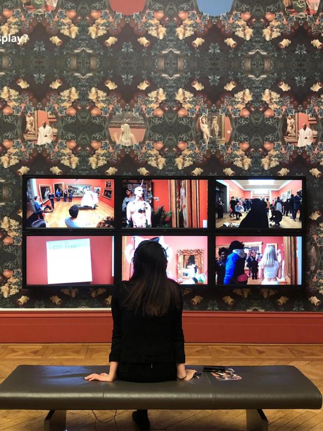 woman sat on bench in art gallery looking up at art