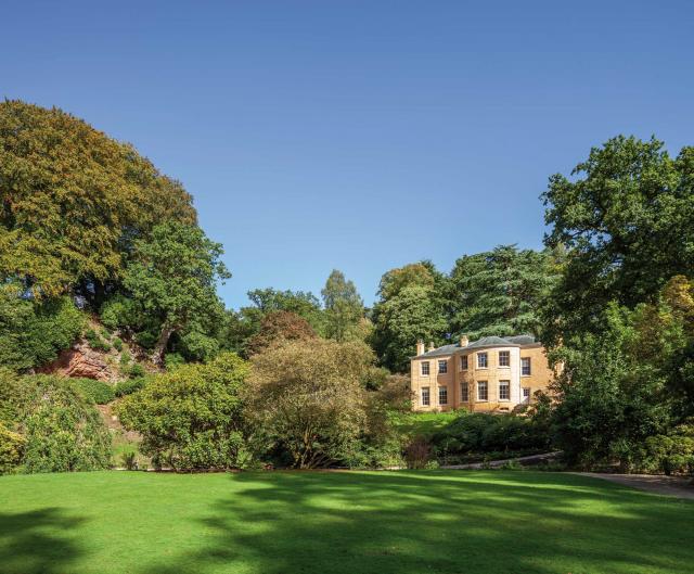 exterior of quarry bank mill house, wide open lawn and a number of trees