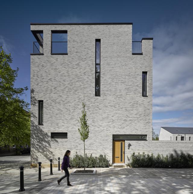 exterior of timekeepers house, grey brick and narrow windows with roof type balcony/terrace