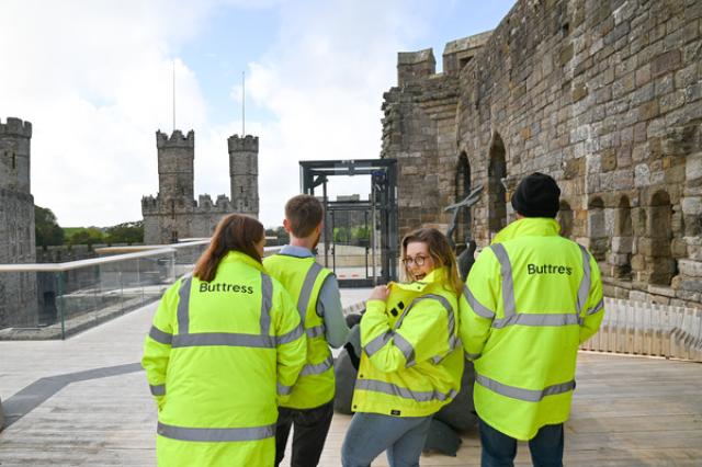 a group of people stand in hi vis jackets on top of a castle