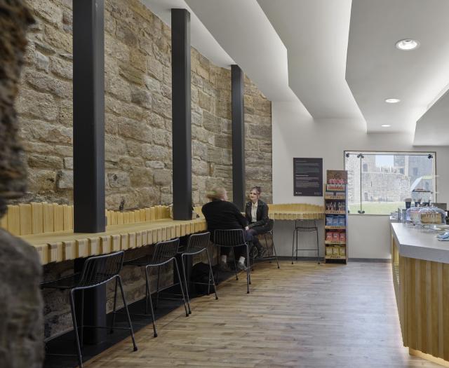 a cafe with stone wall to the left and a sculptural white ceiling