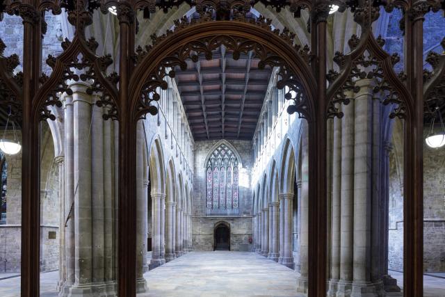 looking down the aisle of a church through a decorative wooden screen