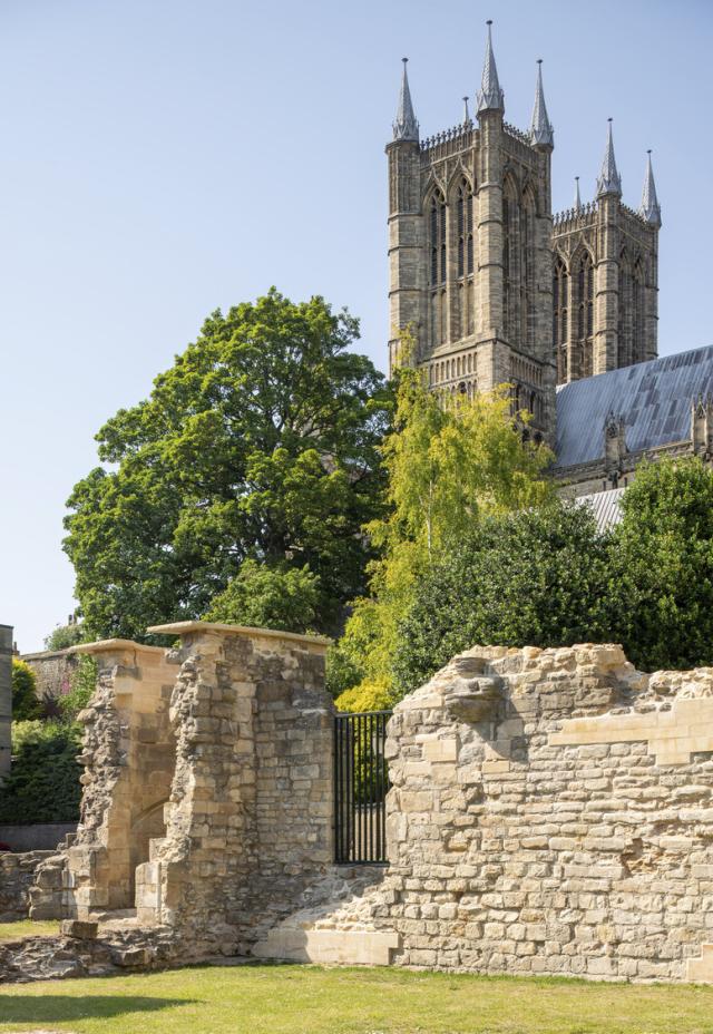 the wall of a medieval ruin is seen with lincoln cathedral in the background