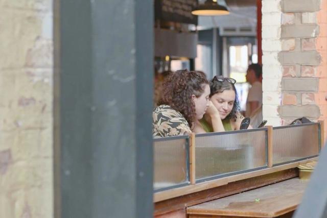 two ladies sitting at a high bar that sits in an open brick arch