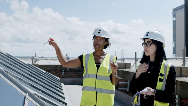 two ladies in high vis and hard hats discuss a project