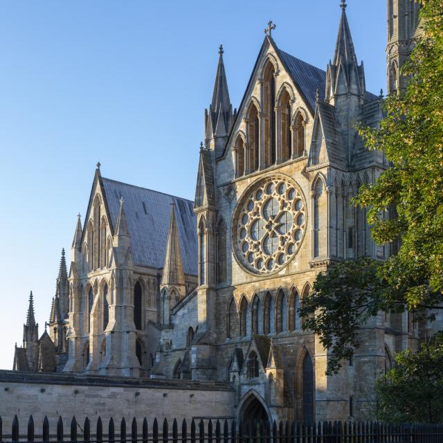 the sun shines on the gable of lincoln cathedral with a blue sky behind