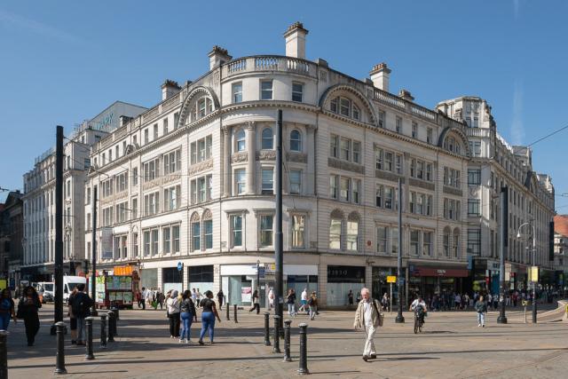 the outside of a city centre historic commercial building constructed of white stone