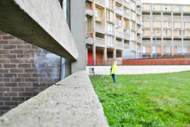 a lady in a high vis jacket is in the distance looking up at Park Hill housing in Sheffield