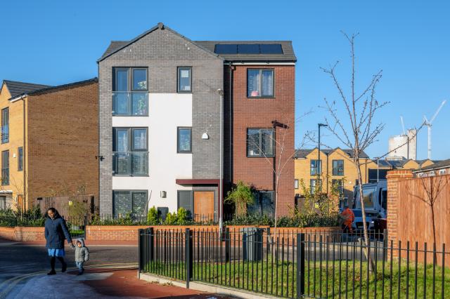 a parent and child walk in front of new houses