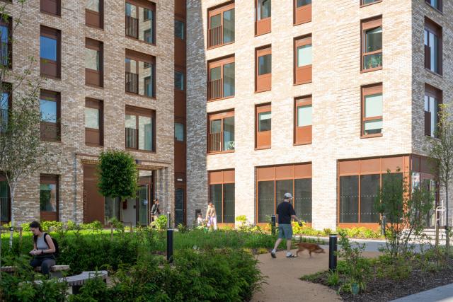 people move through the green space leading to the front door of 'Greenhaus' apartments in Salford