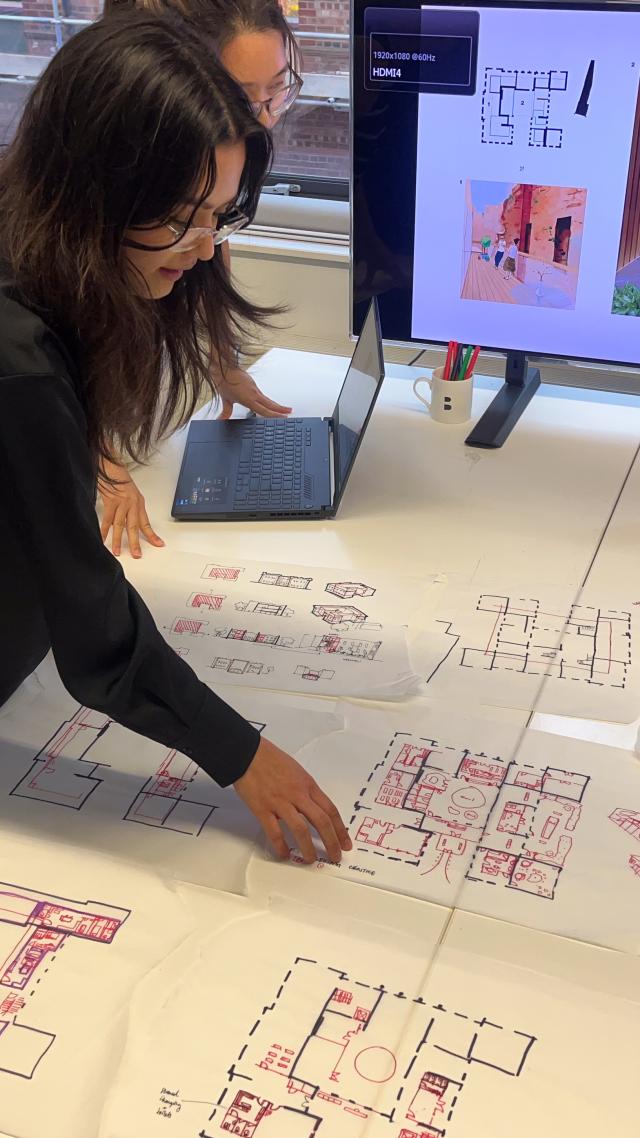 Two girls looking at site plans on a white table