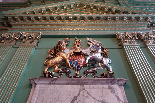 Green wall background with lined columns and logo of two horses.