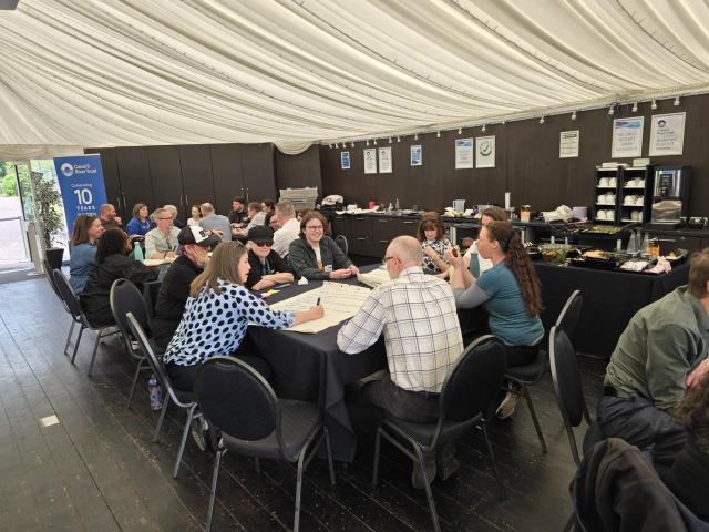 A group of people gathered around a table in a room, workshopping ideas.