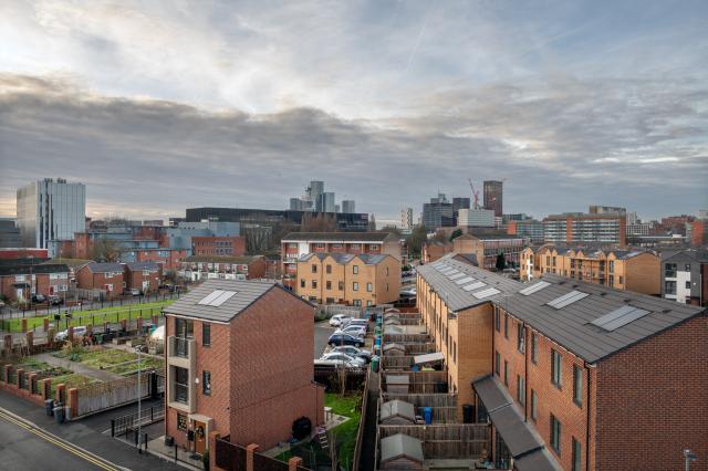 Brunswick neighbourhood, a collection of brick houses and green space with Manchester skyline in the background