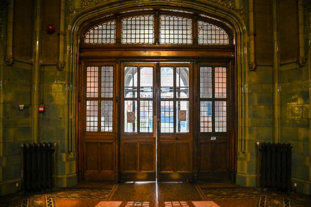 Double dark wood panelled doors with glass windows, and its shadow on orange floor