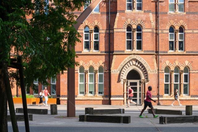 Ancoats Dispensary - a red brick Victorian building with people walking in front of it
