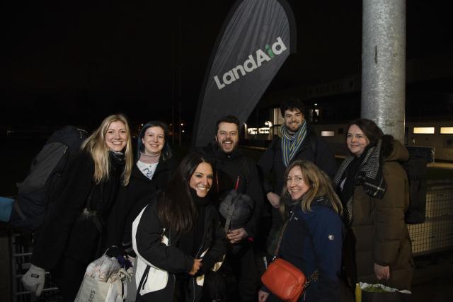 Group photo of people standing in front of a LandAid flag