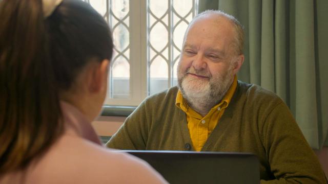 A man wearing a yelllow shirt smiling