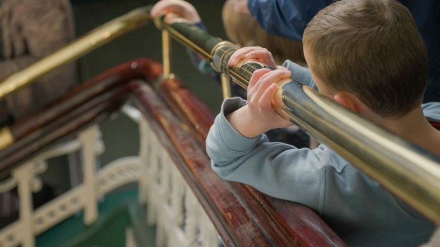 a boy walking down the stairs, focus on his hands on a handrail