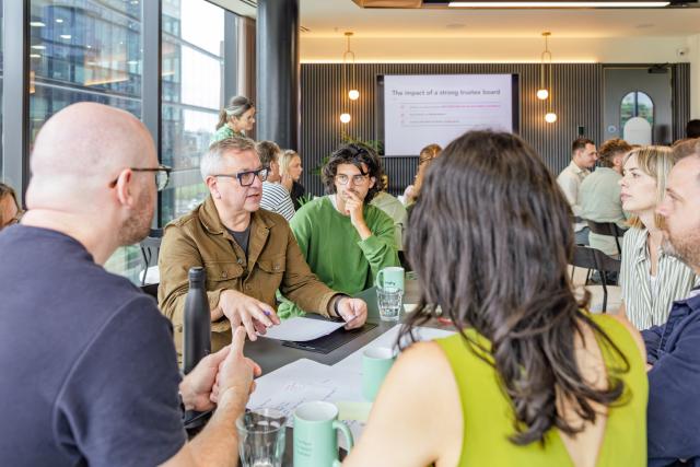 A group of people sitting around a table with papers on the table.