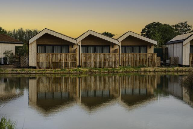 Three wooden lodges overlooking water