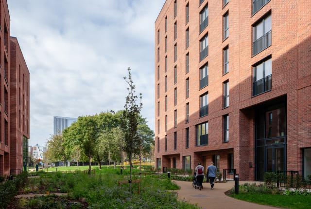 Exterior of No.1 Ancoats Green - a red brick residential development with landscaping and green space outside.