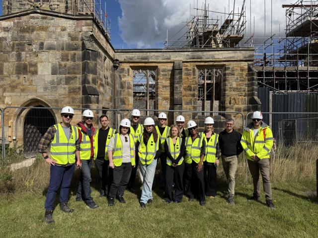 a group of people in hi vis jackets in front of a ruined church