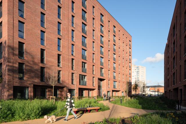 Exterior of a red brick building with a person walking a dog in the forefront
