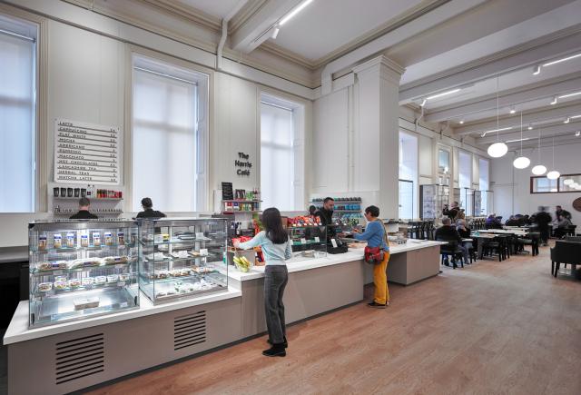 Shelves and display tables stocked with books, stationery, and gifts, with several people browsing in a well-lit retail area.