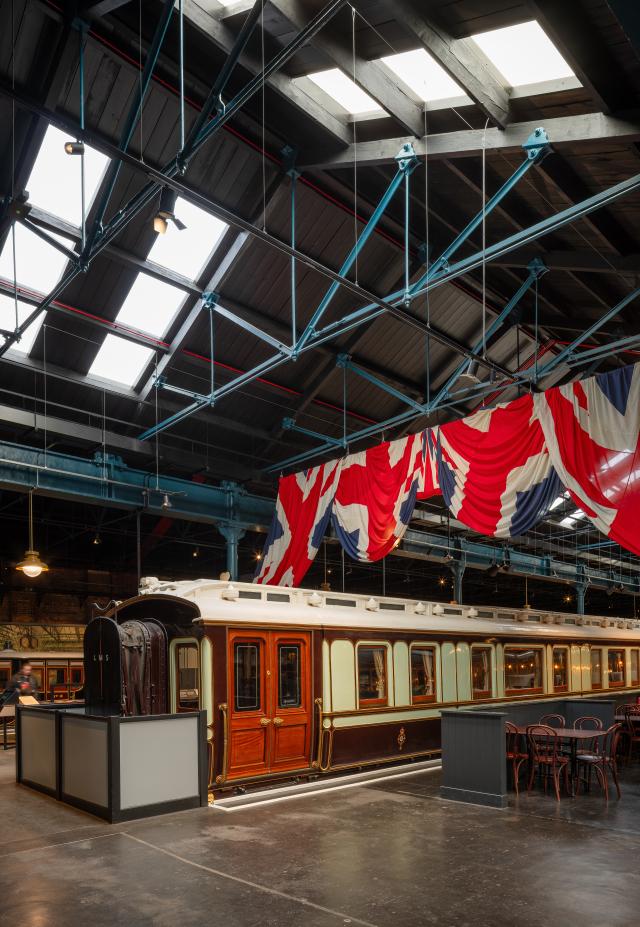 A view of inside the station hall and union jack draped above a train.